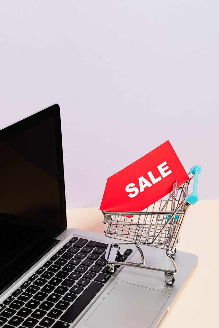 Mini shopping cart with sale tag on laptop for online shopping theme.